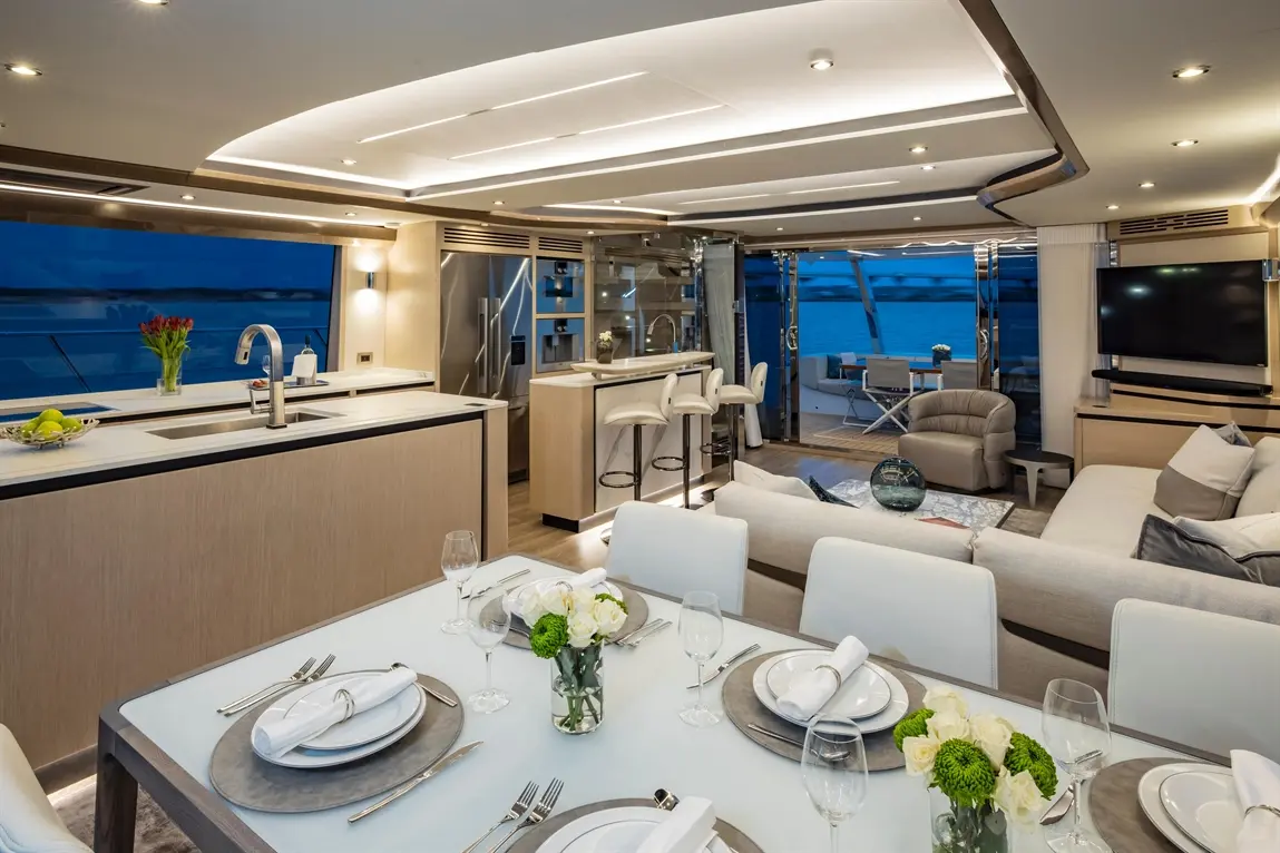 Luxurious yacht interior featuring a modern kitchen, elegant dining setup, and a view of the water through large windows.